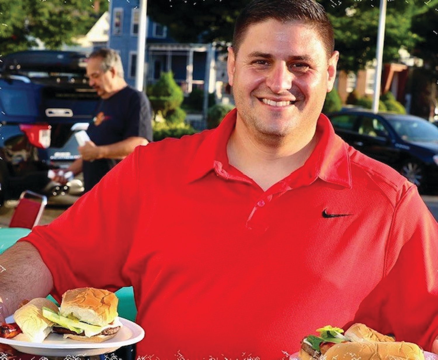 TASTY TREATS: Former Johnston Town Councilman Richard J. DelFino III shows off the cheeseburgers and hot dogs he and 150 people enjoyed last Friday night during the Italo-American Club’s cookout/clambake in Providence.